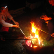 Menschen beim Stockgrillen am offenen Feuer