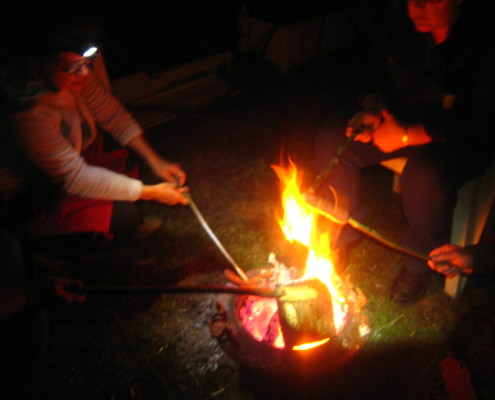 Menschen beim Stockgrillen am offenen Feuer