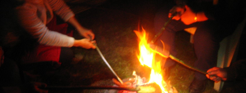 Menschen beim Stockgrillen am offenen Feuer