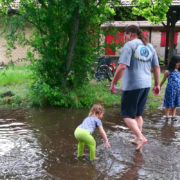 Daniel und zwei Kinder in einem aus Regenwasser entstandenen Planschbecken