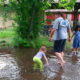 Daniel und zwei Kinder in einem aus Regenwasser entstandenen Planschbecken