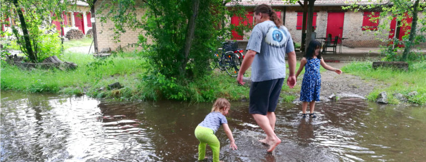 Daniel und zwei Kinder in einem aus Regenwasser entstandenen Planschbecken