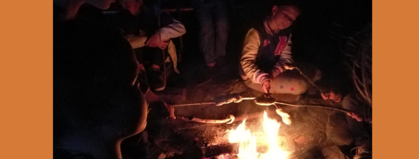Kinder beim Stockbrot grillen am Lagerfeuer