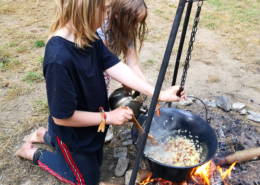 zwei Kinder kochen am Feuer