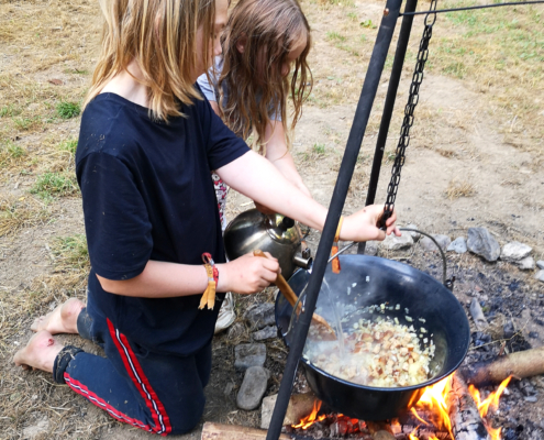 zwei Kinder kochen am Feuer