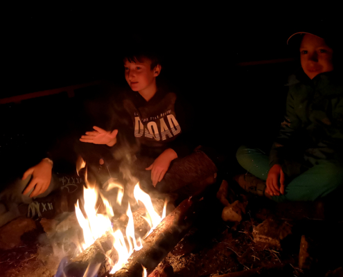 Kinder sitzen am Feuer III