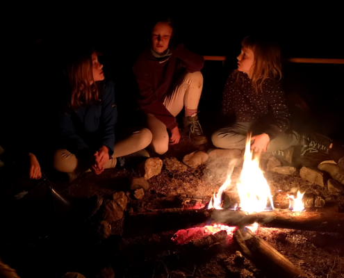 Kinder sitzen am Feuer II