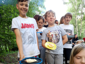 Kinder stehen Schlange mit ihren Pizzen