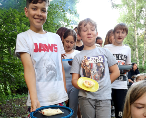 Kinder stehen Schlange mit ihren Pizzen